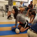 Student practicing chest compression on dummy doll