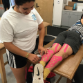 Student putting Athletes tape on leg