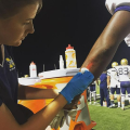 Student disinfecting football players cut on arm