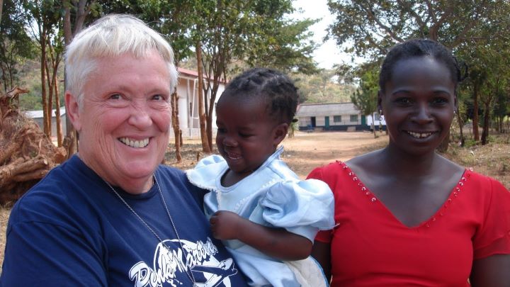 Audrey Spindler holding African Child with their mother for a picture. 