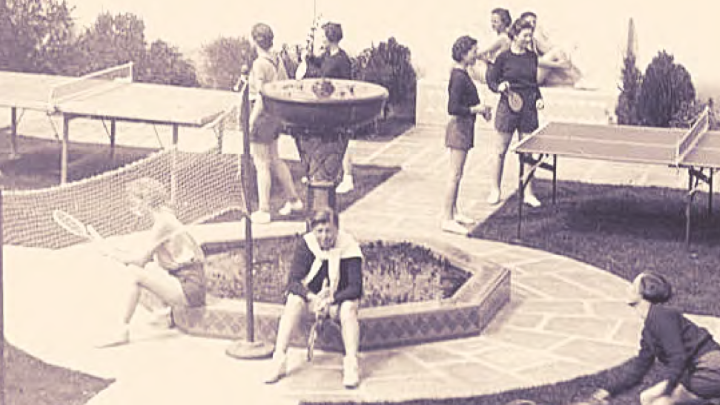 Students sitting around fountain with a racket ball net and paddles