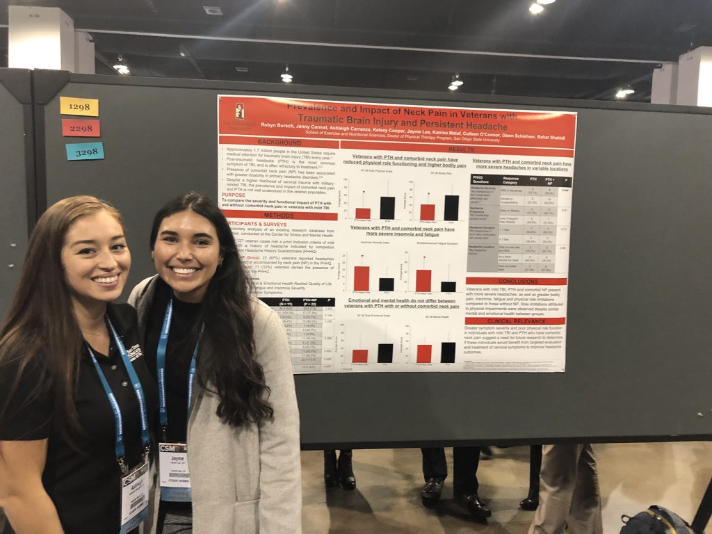 Two students smiling in front of their research poster
